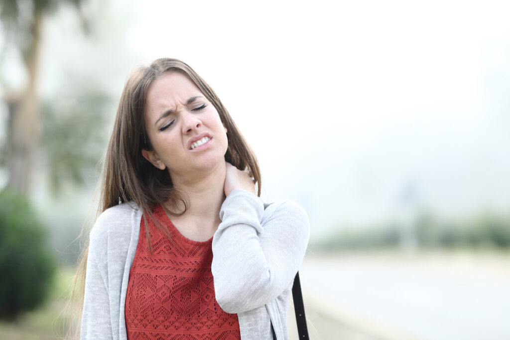 a woman suffering from neck while walking