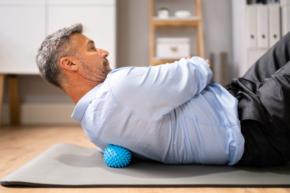 a old man using a spikey ball to his back